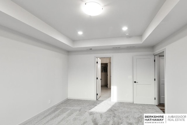 unfurnished bedroom featuring light colored carpet and a raised ceiling