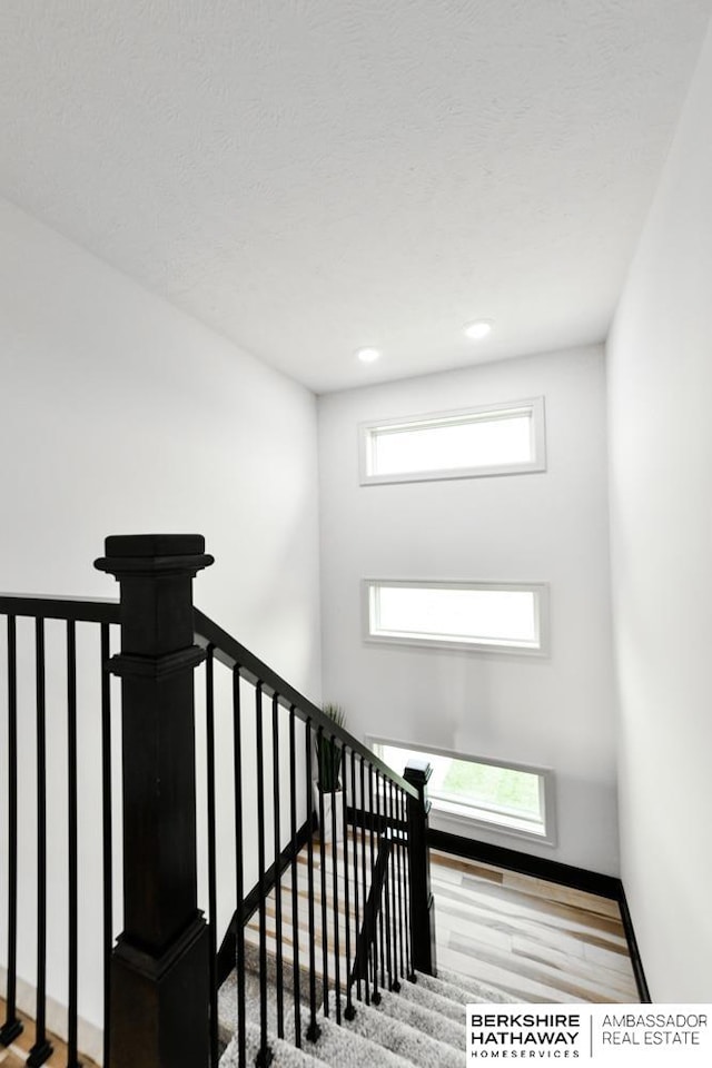 stairway with hardwood / wood-style flooring and a textured ceiling