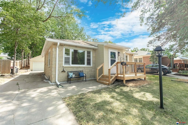 view of front of home with a garage, a deck, a front lawn, and an outbuilding