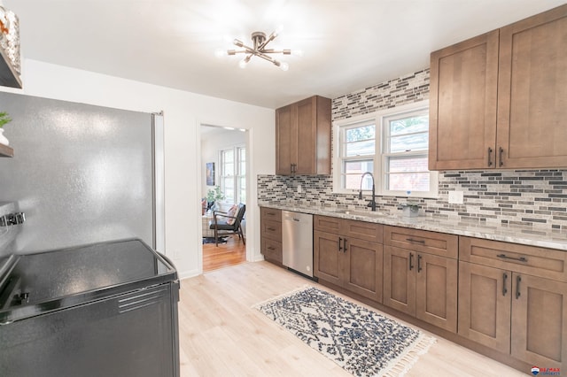 kitchen featuring dishwasher, light hardwood / wood-style flooring, sink, decorative backsplash, and light stone counters