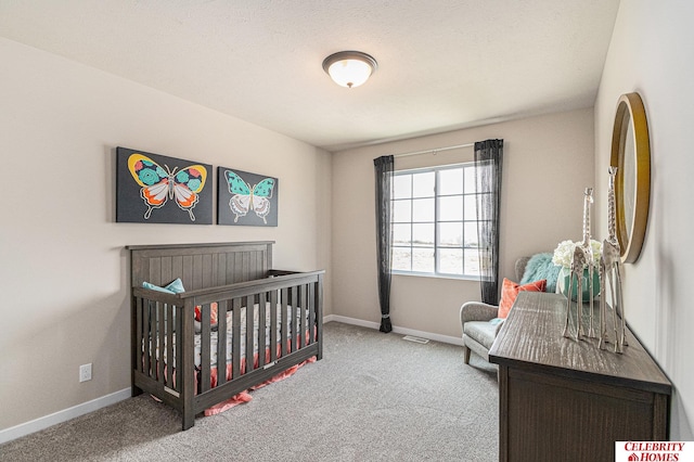 carpeted bedroom featuring a textured ceiling and a crib