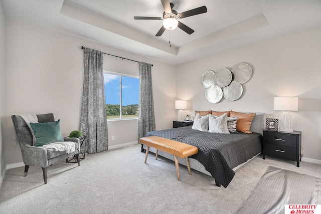 carpeted bedroom with a raised ceiling and ceiling fan