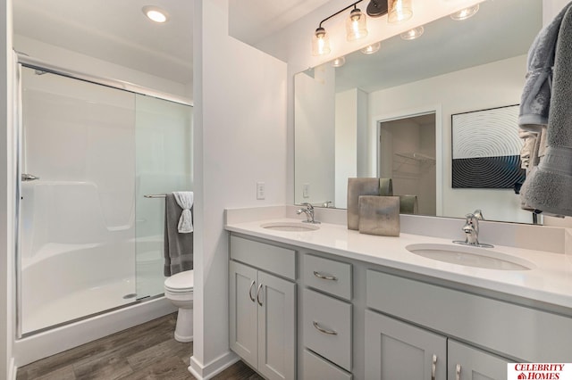 bathroom with hardwood / wood-style floors, walk in shower, toilet, and vanity