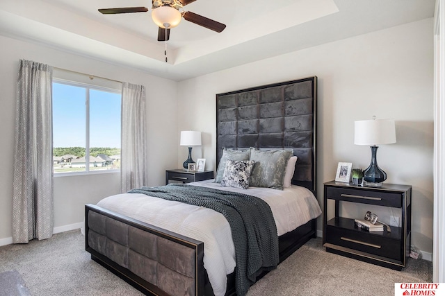 bedroom featuring ceiling fan, a raised ceiling, and light carpet