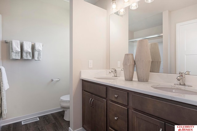 bathroom featuring toilet, hardwood / wood-style flooring, a shower with door, and vanity