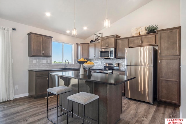 kitchen featuring dark wood-type flooring, appliances with stainless steel finishes, hanging light fixtures, and tasteful backsplash