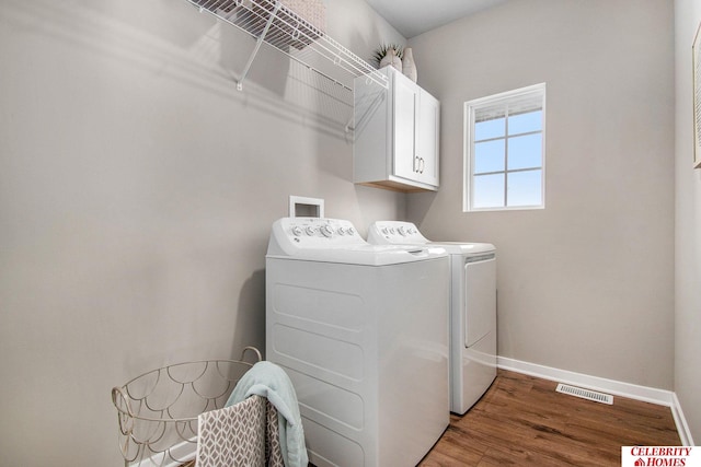 clothes washing area with washer and dryer, cabinets, and hardwood / wood-style floors