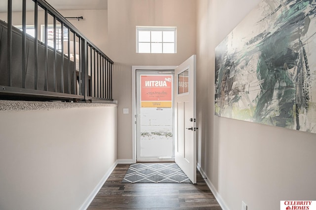 doorway with a towering ceiling and dark wood-type flooring