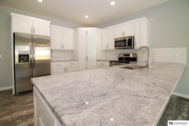 kitchen featuring white cabinets, stainless steel appliances, dark wood-type flooring, and kitchen peninsula