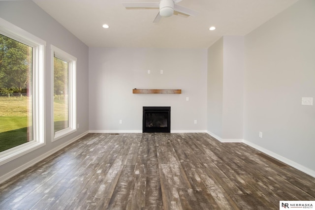 unfurnished living room featuring ceiling fan, dark hardwood / wood-style floors, and a healthy amount of sunlight