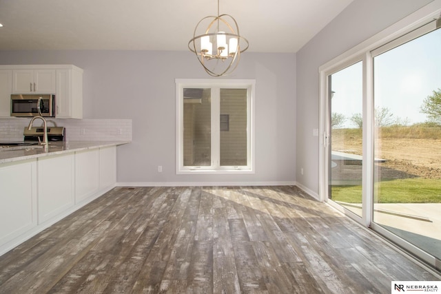 unfurnished dining area with hardwood / wood-style floors and a notable chandelier