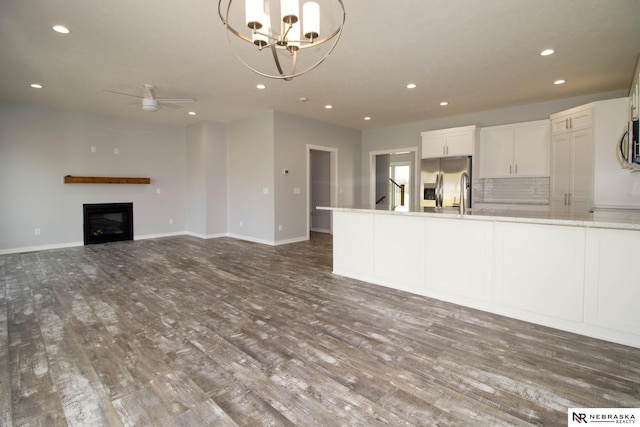 kitchen with ceiling fan with notable chandelier, white cabinetry, appliances with stainless steel finishes, and hardwood / wood-style floors