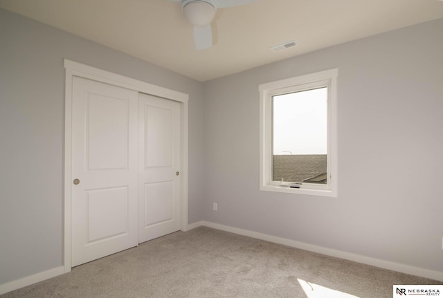 unfurnished bedroom featuring ceiling fan, light colored carpet, and a closet