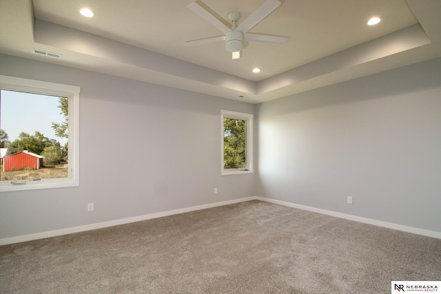 carpeted empty room with a tray ceiling and ceiling fan