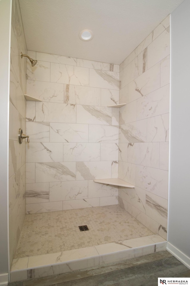 bathroom featuring hardwood / wood-style floors and a tile shower