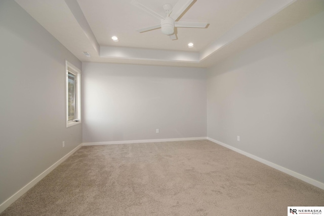 carpeted empty room with a tray ceiling and ceiling fan