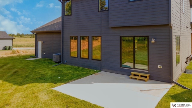 rear view of property with a lawn, cooling unit, and a patio area