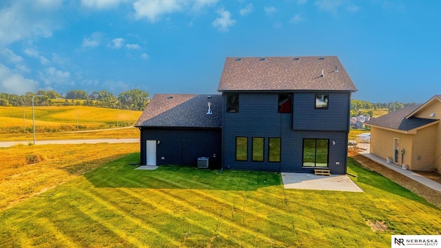 rear view of house with a patio, cooling unit, a rural view, and a yard