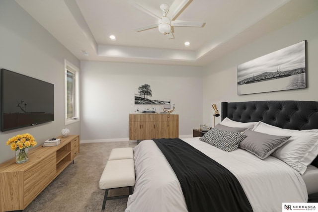 carpeted bedroom with ceiling fan and a raised ceiling