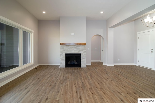 unfurnished living room featuring wood-type flooring and a stone fireplace