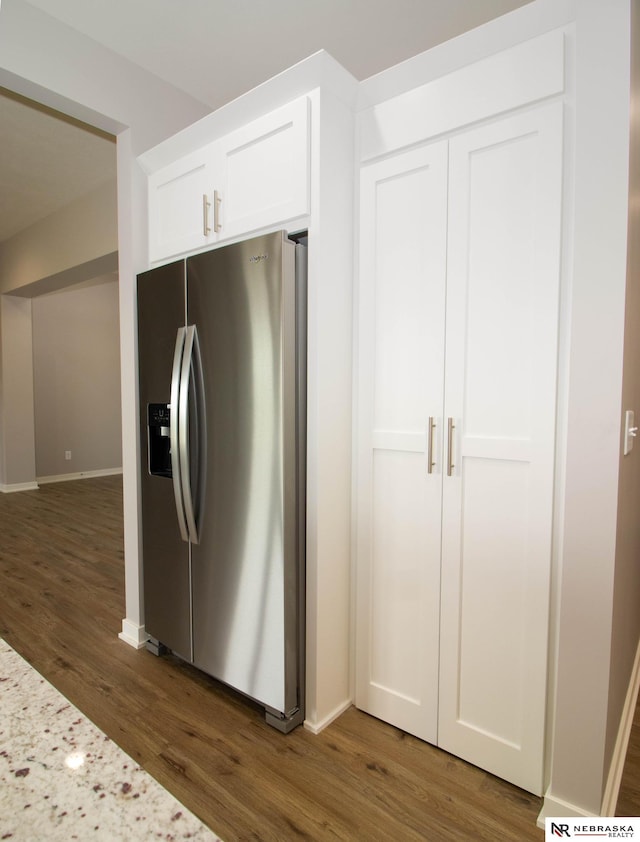 kitchen with light stone counters, white cabinets, stainless steel refrigerator with ice dispenser, and dark hardwood / wood-style flooring