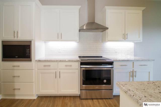 kitchen with wall chimney exhaust hood, white cabinets, stainless steel electric range, and light hardwood / wood-style floors