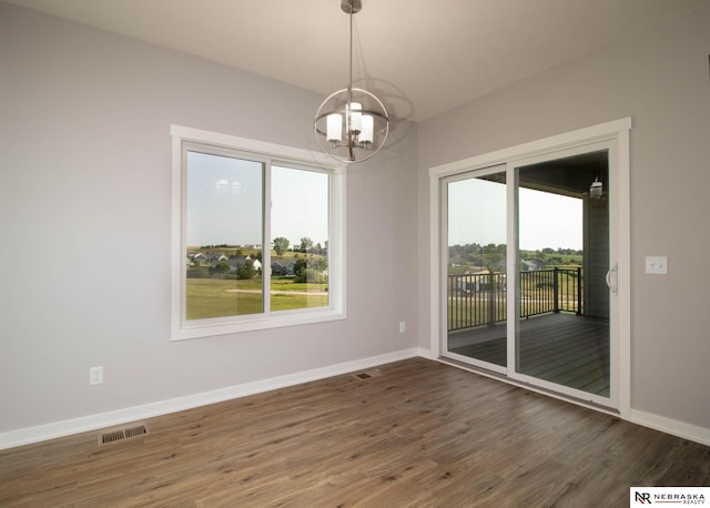 spare room with dark wood-type flooring and a notable chandelier