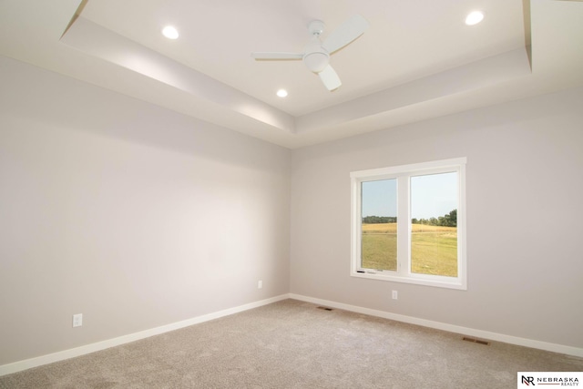 carpeted empty room with a tray ceiling and ceiling fan