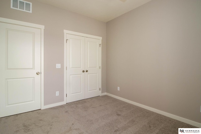 unfurnished bedroom featuring light colored carpet and a closet