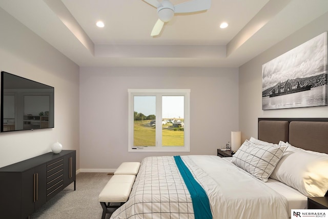 carpeted bedroom featuring ceiling fan and a raised ceiling