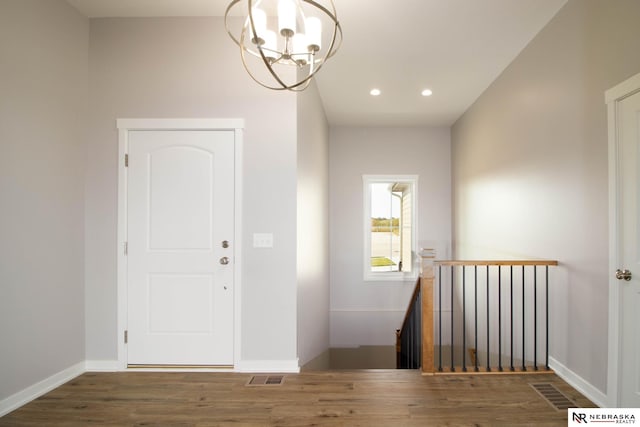 stairs with wood-type flooring and an inviting chandelier