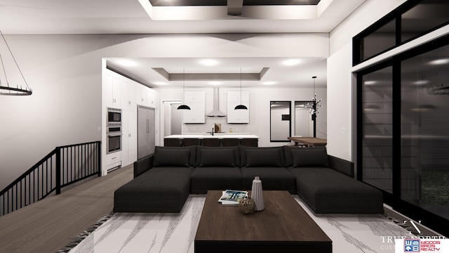 living room with a raised ceiling, sink, and light hardwood / wood-style floors