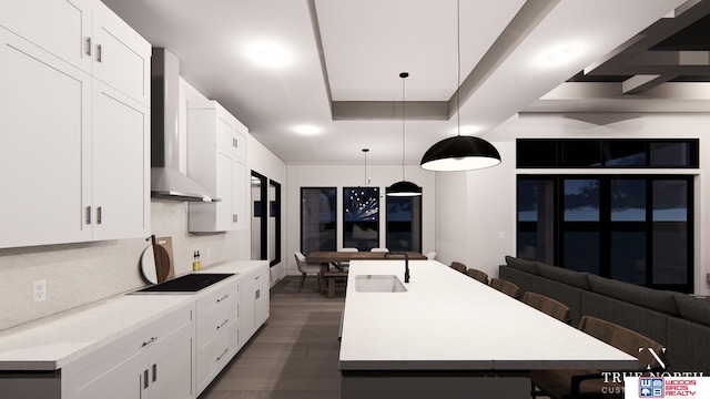 kitchen featuring an island with sink, hanging light fixtures, and white cabinets