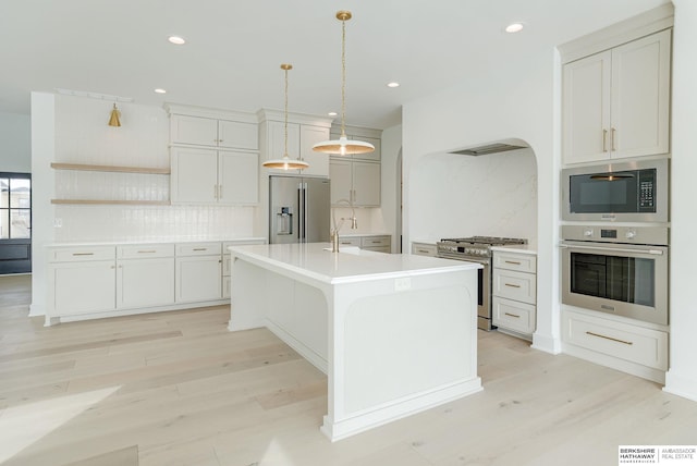 kitchen featuring appliances with stainless steel finishes, decorative backsplash, light wood-style flooring, and light countertops