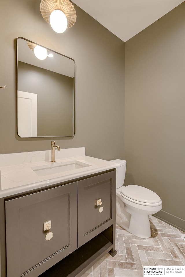 bathroom with baseboards, toilet, and vanity