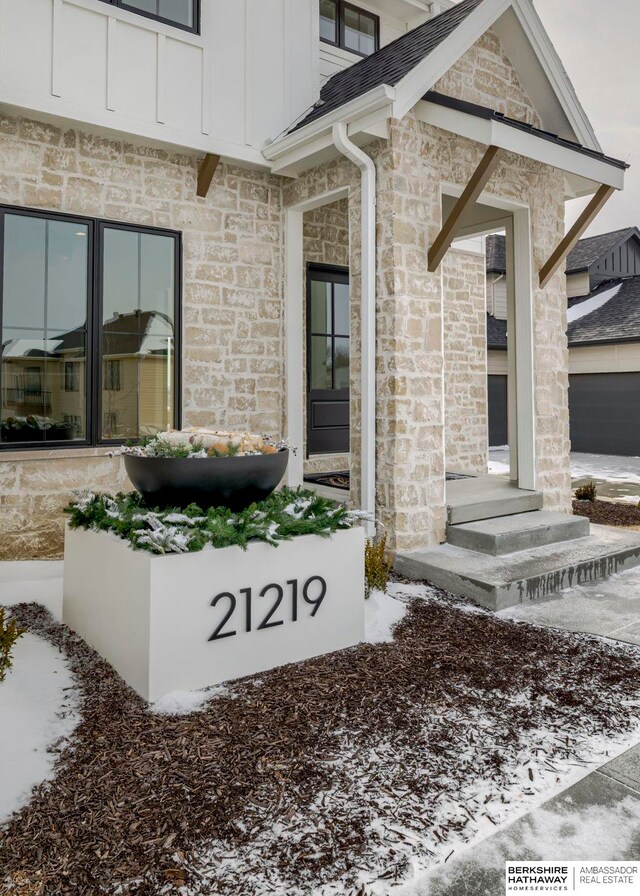 doorway to property featuring board and batten siding and stone siding