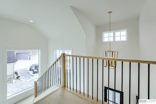 hall with a notable chandelier, an upstairs landing, and lofted ceiling