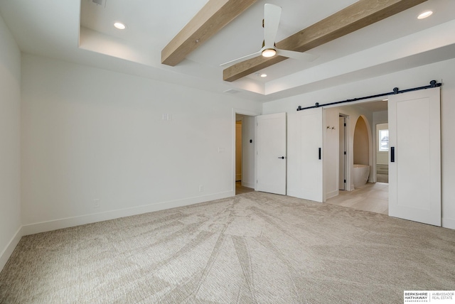 unfurnished bedroom featuring a barn door, arched walkways, light colored carpet, and recessed lighting