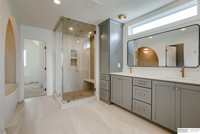 bathroom with a tub, a shower stall, double vanity, a sink, and visible vents