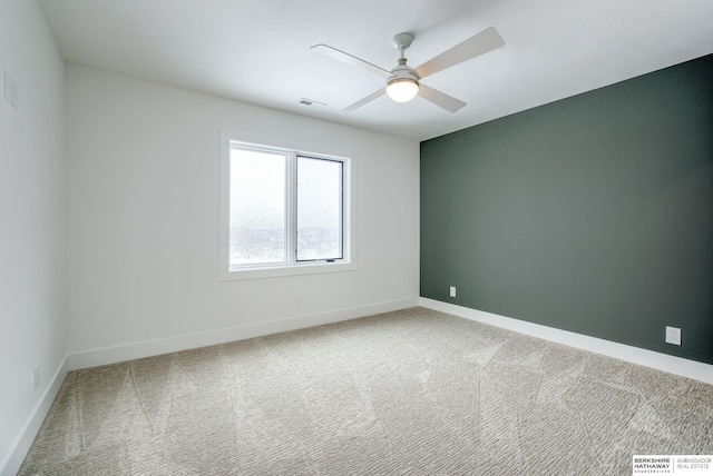 carpeted empty room featuring visible vents, a ceiling fan, and baseboards