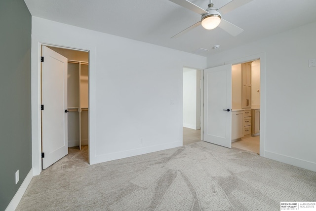 unfurnished bedroom featuring a walk in closet, baseboards, ensuite bathroom, and carpet flooring