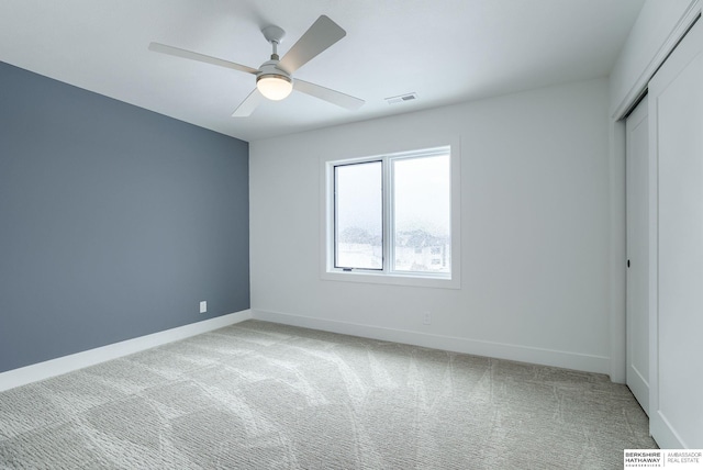unfurnished bedroom with a closet, light carpet, ceiling fan, baseboards, and visible vents