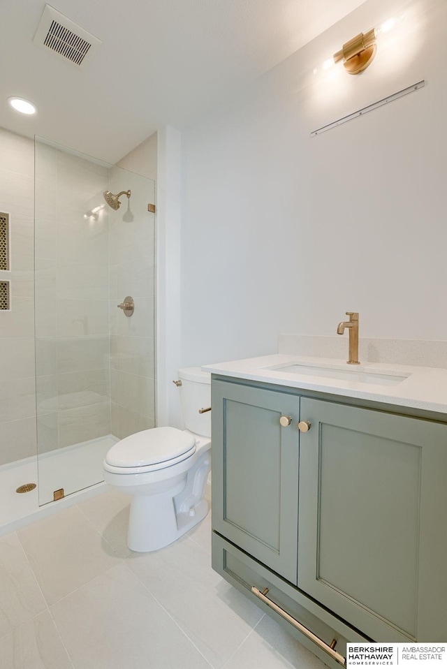 bathroom featuring a tile shower, tile patterned flooring, toilet, vanity, and visible vents