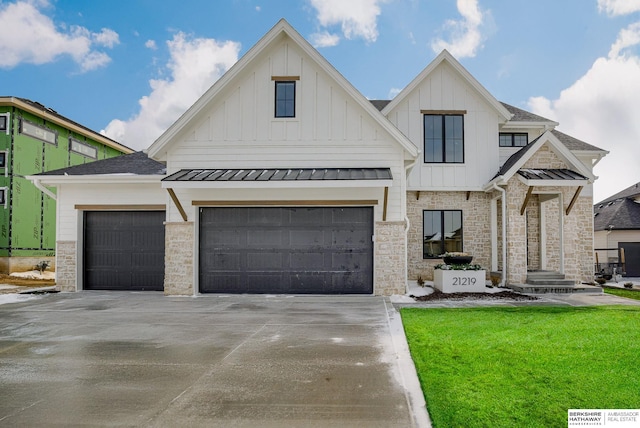 view of front of property featuring a standing seam roof, concrete driveway, board and batten siding, and stone siding
