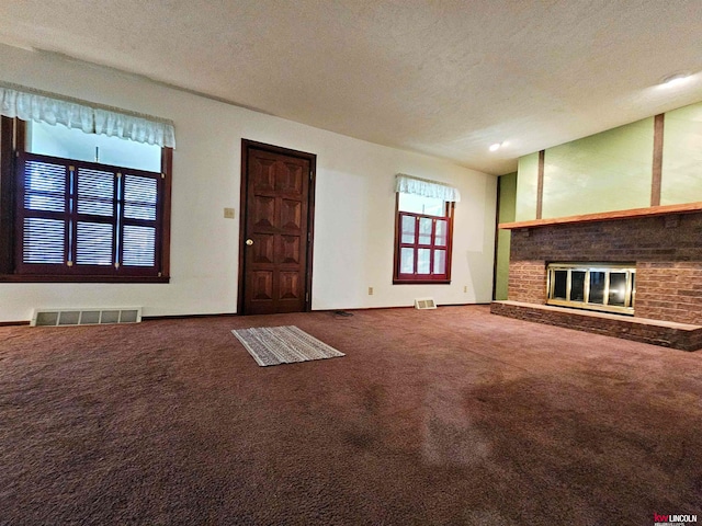 unfurnished living room featuring a textured ceiling, carpet, and a brick fireplace