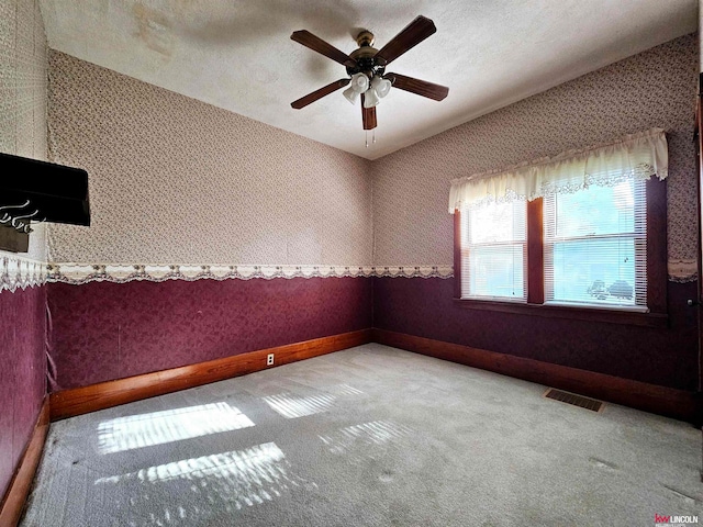 carpeted empty room with a textured ceiling and ceiling fan