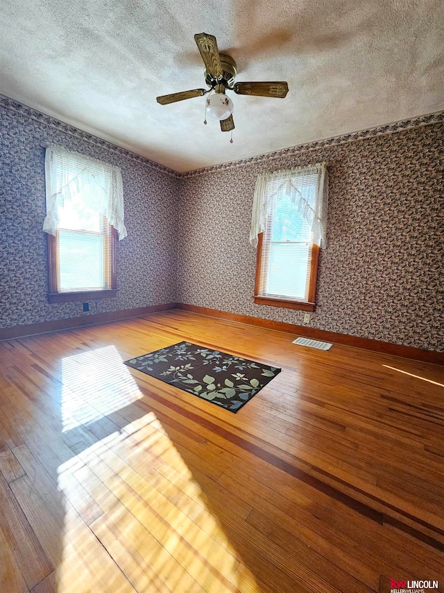 spare room featuring ceiling fan, hardwood / wood-style flooring, and a textured ceiling