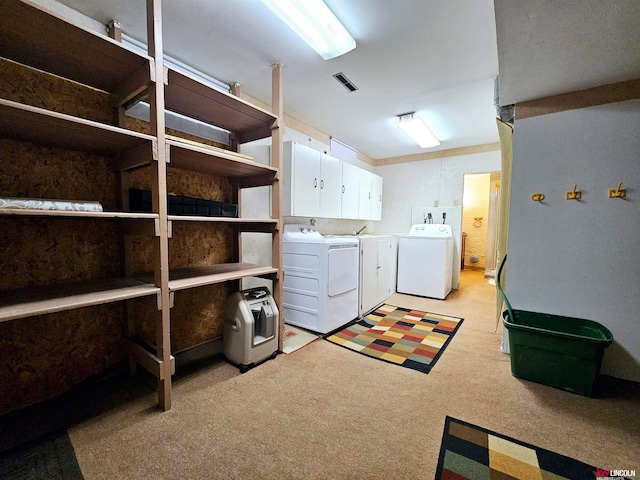 laundry area featuring light carpet, cabinets, and washing machine and dryer