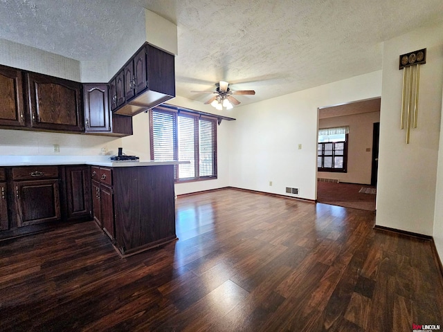 kitchen featuring a textured ceiling, dark brown cabinets, kitchen peninsula, ceiling fan, and dark hardwood / wood-style floors