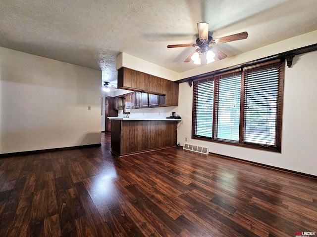 kitchen with ceiling fan, dark hardwood / wood-style flooring, kitchen peninsula, and a textured ceiling